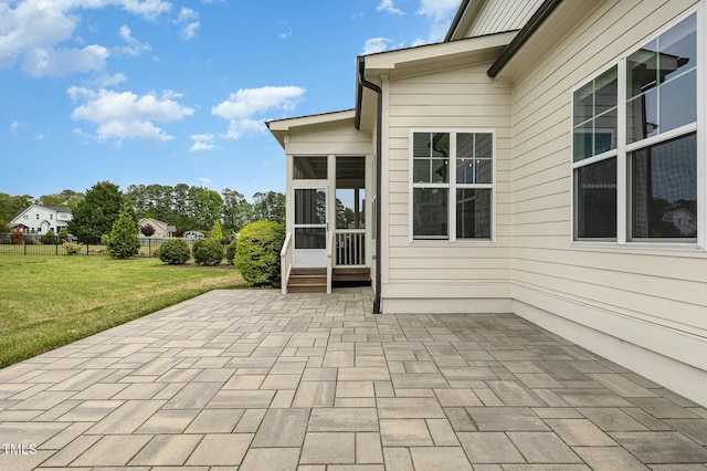 view of patio featuring fence and a sunroom