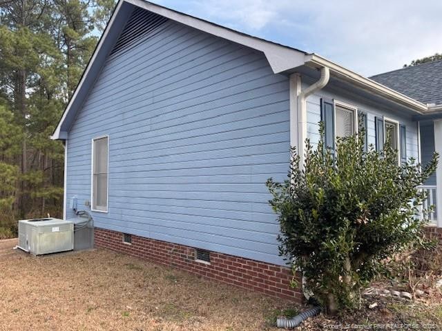 view of side of home with crawl space and a shingled roof