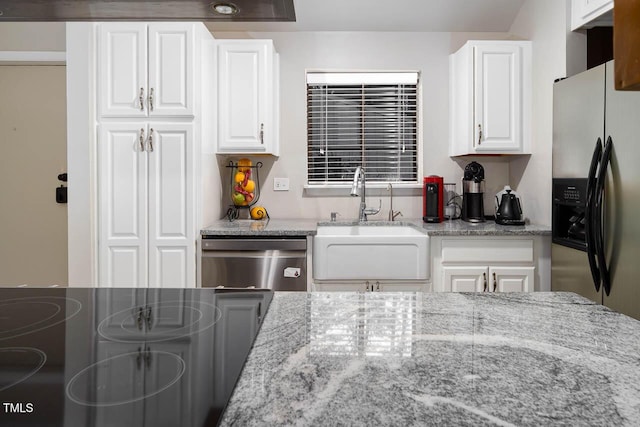 kitchen featuring white cabinetry, light stone counters, appliances with stainless steel finishes, and a sink