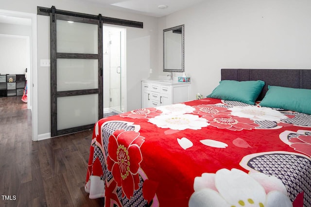 bedroom with dark wood finished floors, a barn door, and baseboards