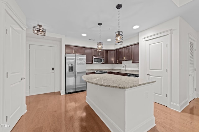 kitchen featuring a sink, stainless steel appliances, dark brown cabinetry, light wood finished floors, and hanging light fixtures