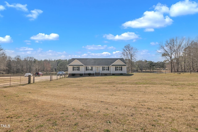 ranch-style home with a wooded view, a front lawn, and fence