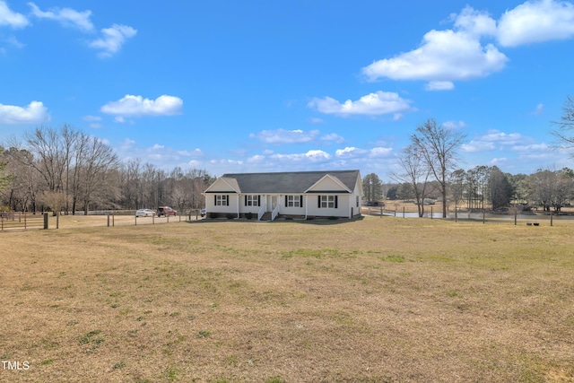 view of front facade featuring a rural view, a front yard, and fence