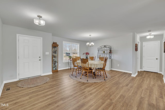 dining space featuring a notable chandelier, light wood-style floors, visible vents, and baseboards