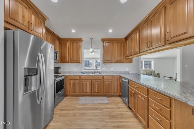 kitchen with brown cabinets, recessed lighting, stainless steel appliances, light wood-style floors, and a peninsula