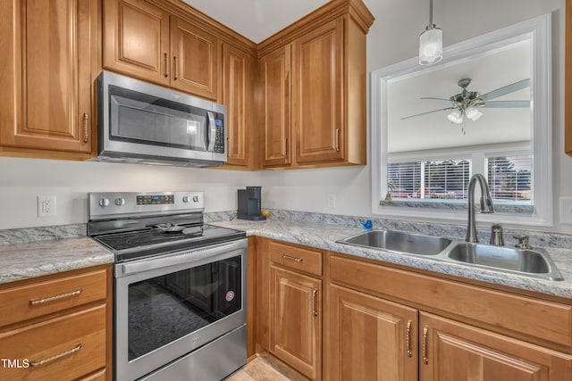 kitchen with a sink, stainless steel appliances, brown cabinetry, and light countertops