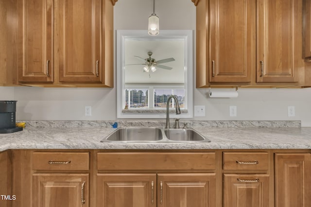 kitchen featuring a sink, brown cabinetry, a ceiling fan, and light countertops