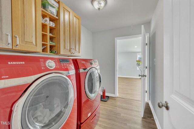 clothes washing area featuring baseboards, cabinet space, separate washer and dryer, and wood finished floors