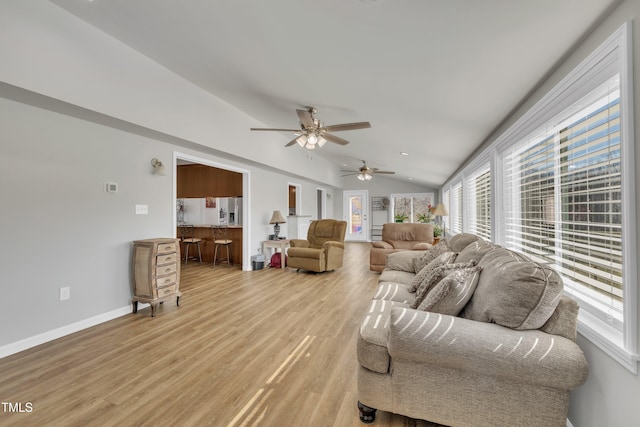 living room featuring baseboards, lofted ceiling, and light wood-style floors