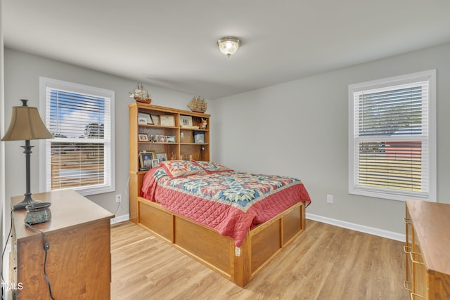 bedroom featuring baseboards, multiple windows, and light wood-style floors