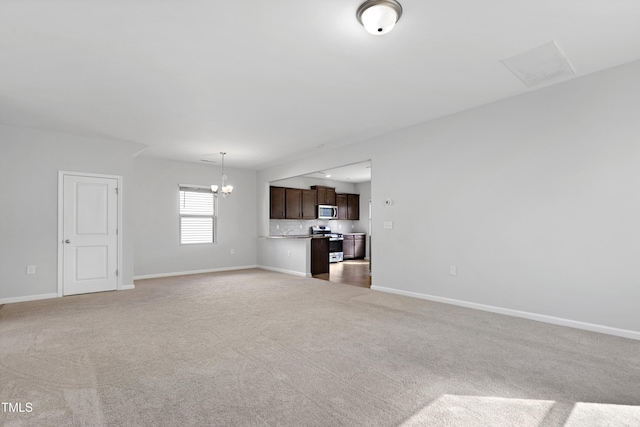 unfurnished living room featuring light colored carpet, baseboards, and an inviting chandelier