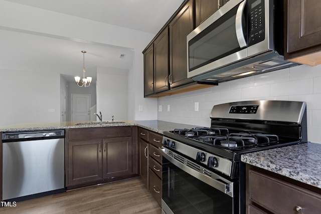 kitchen with a sink, stone countertops, backsplash, stainless steel appliances, and dark brown cabinetry