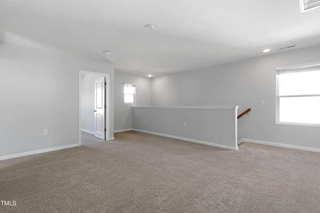 unfurnished room featuring visible vents, baseboards, and light colored carpet