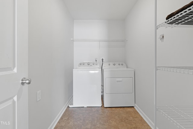 laundry area with laundry area, washer and dryer, and baseboards