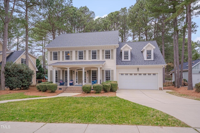 colonial home with a front lawn, roof with shingles, covered porch, an attached garage, and concrete driveway