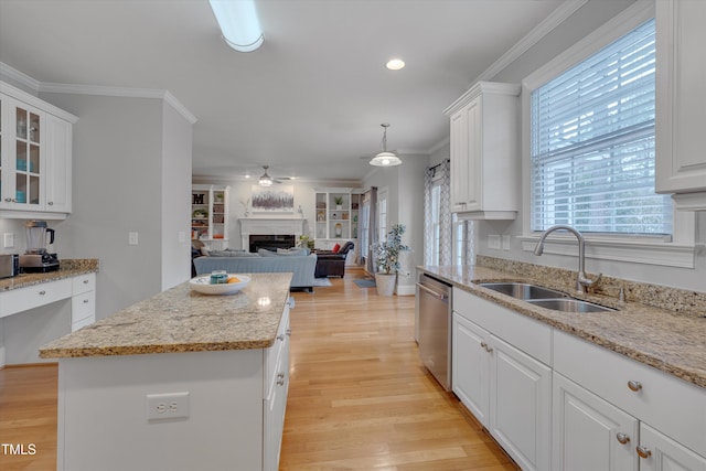 kitchen featuring stainless steel dishwasher, ornamental molding, light wood-style floors, and a sink