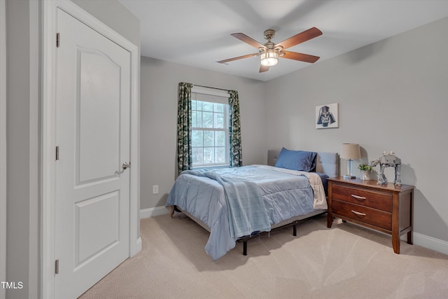 bedroom with light carpet, a ceiling fan, and baseboards