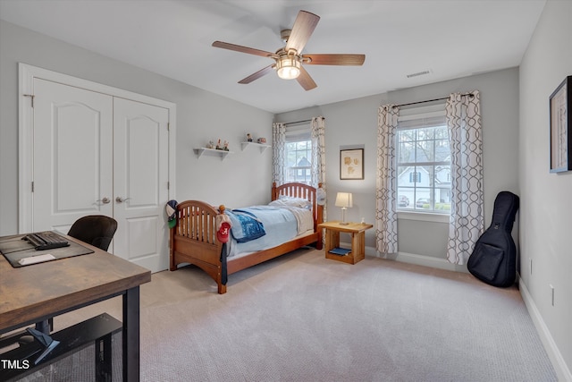 bedroom with visible vents, a ceiling fan, a closet, baseboards, and light colored carpet