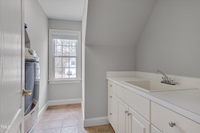 bathroom featuring baseboards, washer / dryer, vanity, and vaulted ceiling