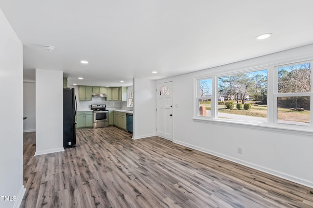 kitchen featuring black appliances, wood finished floors, light countertops, green cabinetry, and baseboards