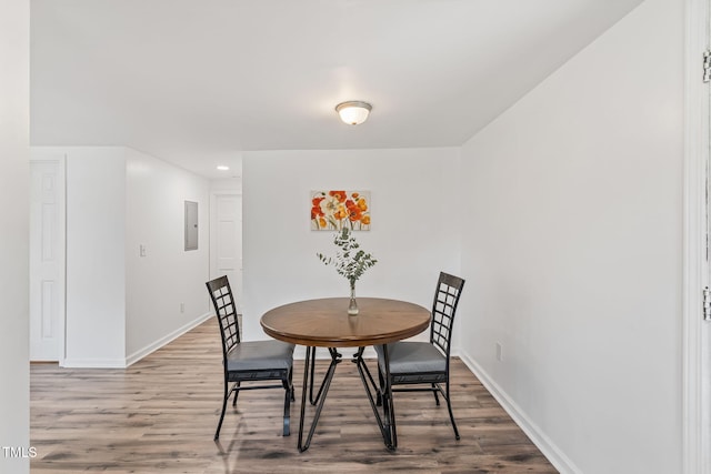 dining room featuring electric panel, baseboards, and wood finished floors