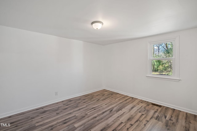 unfurnished room featuring visible vents, baseboards, and wood finished floors