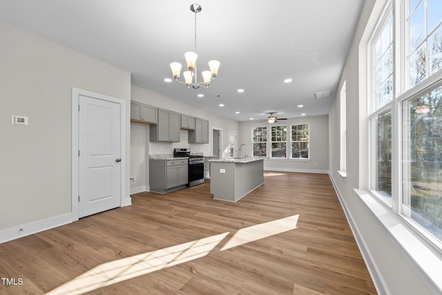 kitchen featuring gray cabinetry, light wood-style flooring, open floor plan, gas range, and baseboards