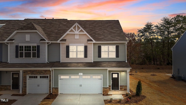 multi unit property featuring concrete driveway, a garage, and stone siding