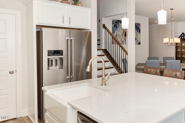 kitchen featuring a notable chandelier, decorative light fixtures, high quality fridge, white cabinets, and light countertops