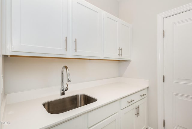 kitchen with light countertops, white cabinets, and a sink