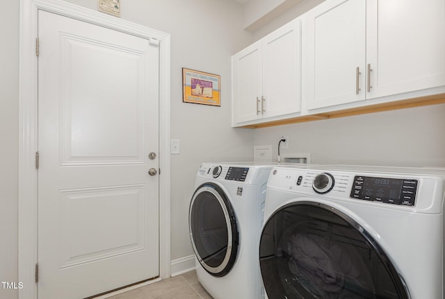 laundry area featuring light tile patterned floors, cabinet space, and washing machine and clothes dryer