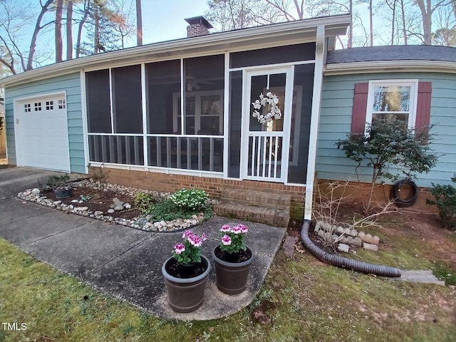 view of side of property featuring an attached garage, a chimney, and a sunroom