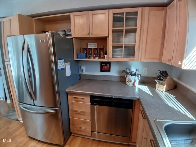 kitchen with light brown cabinets, a sink, open shelves, stainless steel appliances, and light wood finished floors