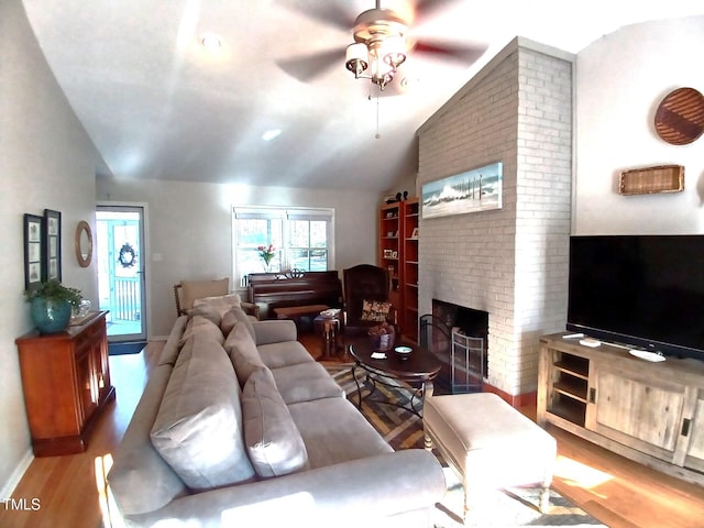 living area with wood finished floors, a fireplace, baseboards, ceiling fan, and vaulted ceiling