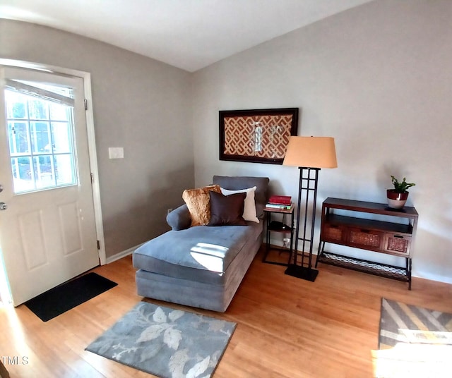 sitting room featuring baseboards, lofted ceiling, and wood finished floors