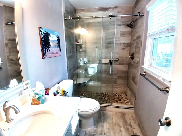 full bath with wood finished floors, toilet, a stall shower, and vanity