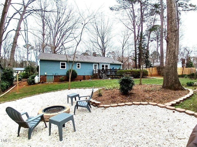 rear view of property with a lawn, a fire pit, and fence