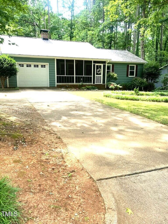 ranch-style home with driveway, a garage, and a sunroom