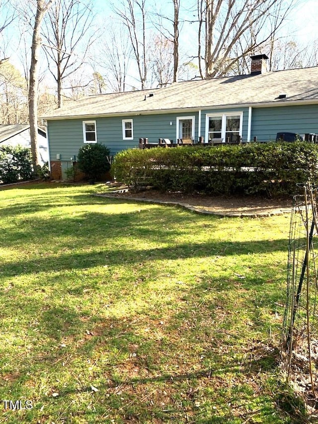 rear view of house with a yard and a chimney