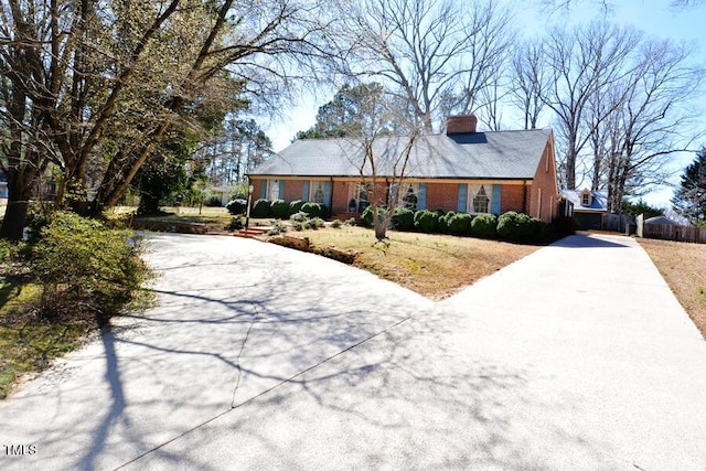 ranch-style home with brick siding, driveway, and a chimney