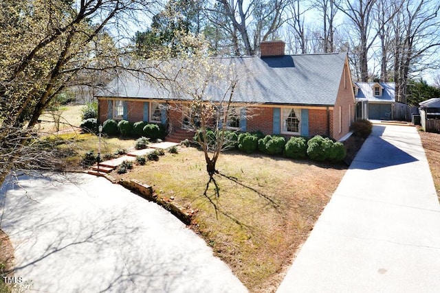 view of front of home featuring concrete driveway, brick siding, and a chimney