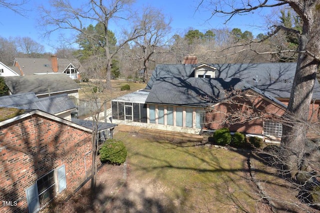 rear view of house featuring brick siding and a sunroom