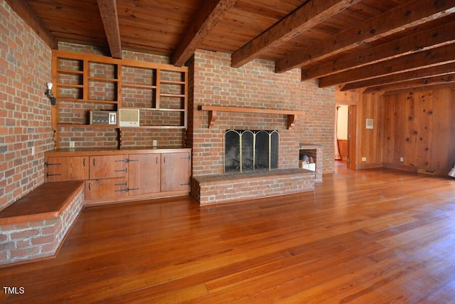 unfurnished living room featuring wood ceiling, beamed ceiling, a brick fireplace, and wood finished floors