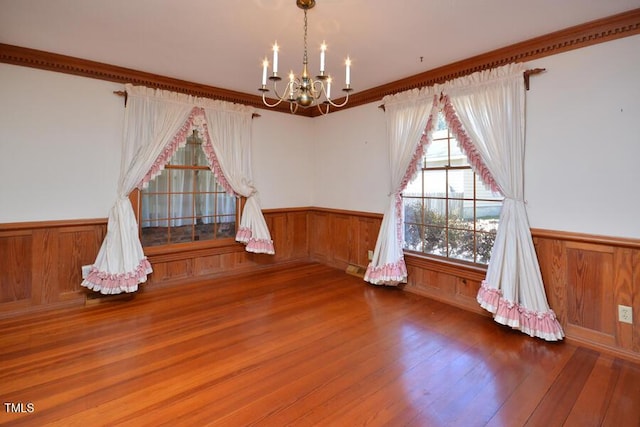 interior space featuring a wainscoted wall, wood finished floors, and a chandelier