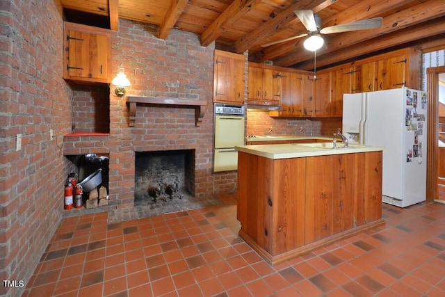 kitchen featuring beamed ceiling, under cabinet range hood, white appliances, wooden ceiling, and a fireplace