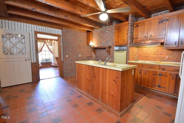 kitchen featuring white appliances, brown cabinetry, under cabinet range hood, and a sink