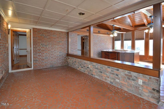 interior space featuring ceiling fan, a paneled ceiling, and brick wall