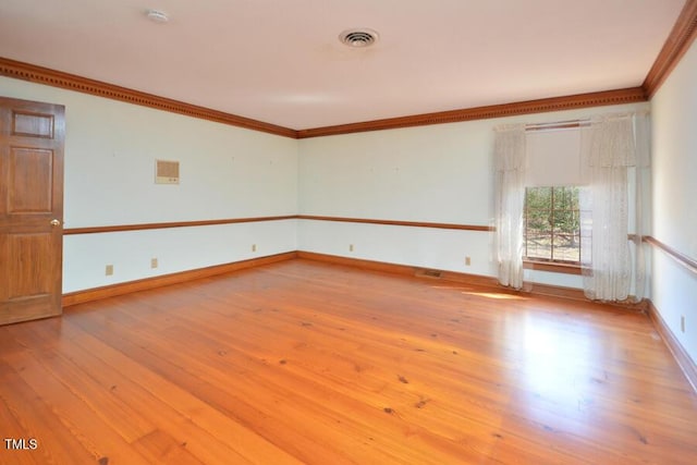 unfurnished room with visible vents, baseboards, ornamental molding, and hardwood / wood-style flooring