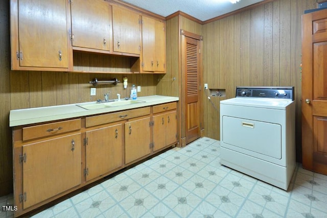 laundry room featuring crown molding, light floors, cabinet space, washer / clothes dryer, and a sink