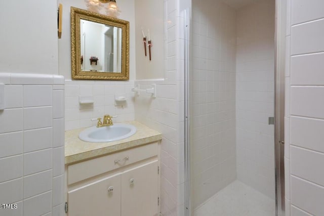 full bathroom with a wainscoted wall, tile walls, a stall shower, and vanity